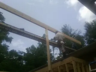 Carpenter setting a ridge beam over a new addition frame — Ice Dam Removal by Roofing Brothers in Mullins