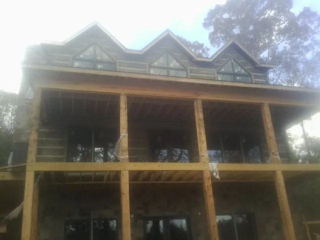 Dormers and porch framing on a large log home under construction — Roof Coating work by our crew in Mullins