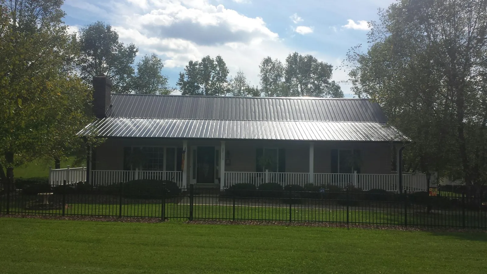Gray metal roof on a brick ranch with a full width front porch — Gutter Guard Installation work by our crew in Mullins