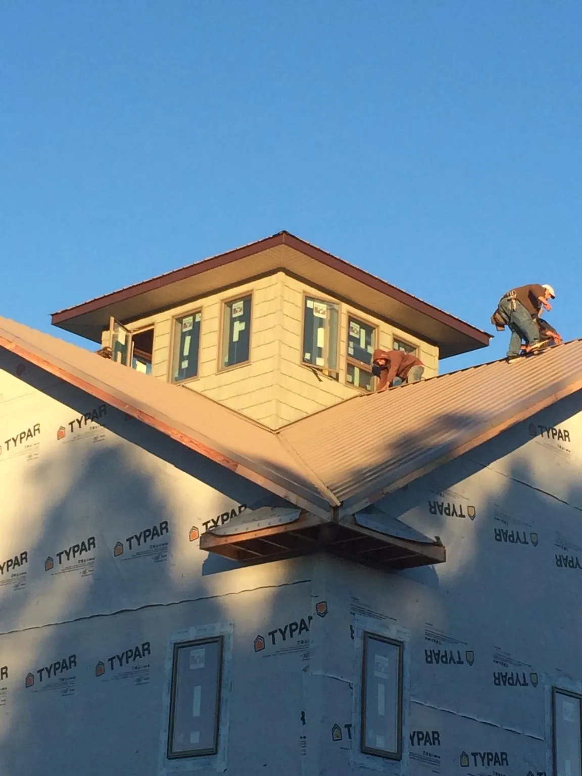 Roofers working around a rooftop cupola on a new metal roof at sunset — Roof Waterproofing in Mullins by Roofing Brothers